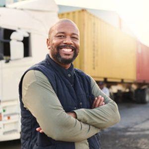 Delivery, container and happy truck driver moving industry cargo and freight at a shipping supply chain or warehouse. Smile, industrial and black man ready to transport ecommerce trade goods or stock